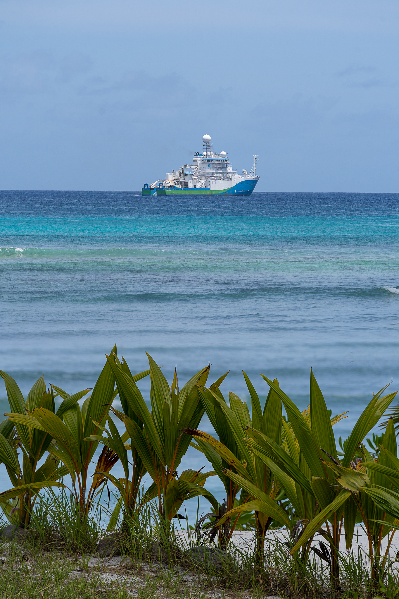 A ship viewed from a tropical island.