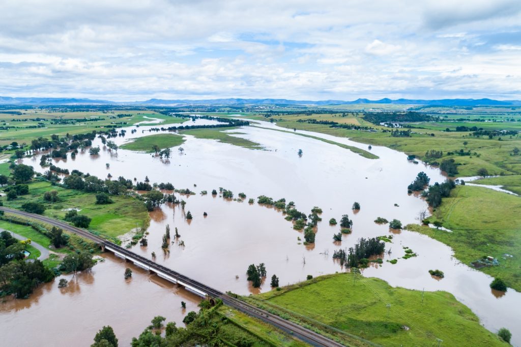 Brown floodwaters covering farmland near Singleton, NSW, Australia.