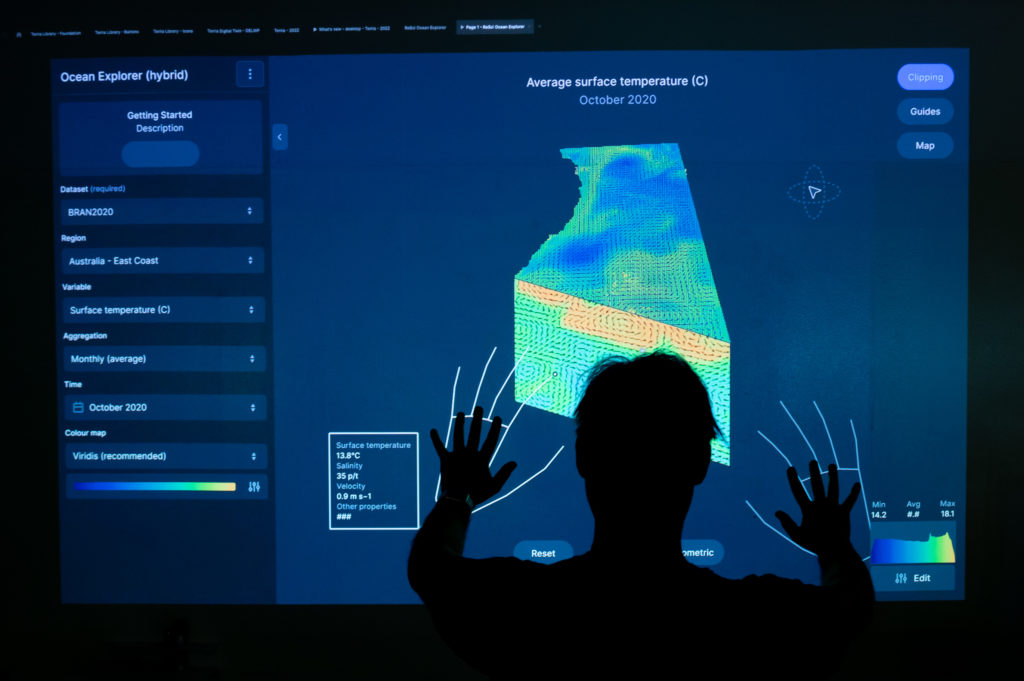A photograph of a person using augmented reality to control a map of the ocean.