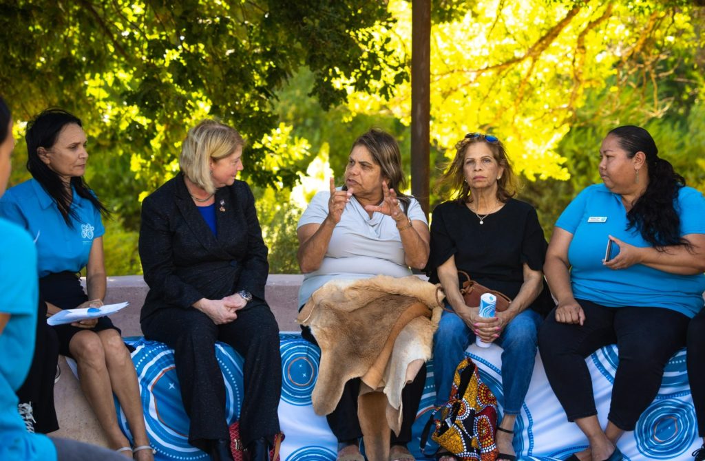 A photo showing a diverse mix of women sitting and talking with each other in a circle.