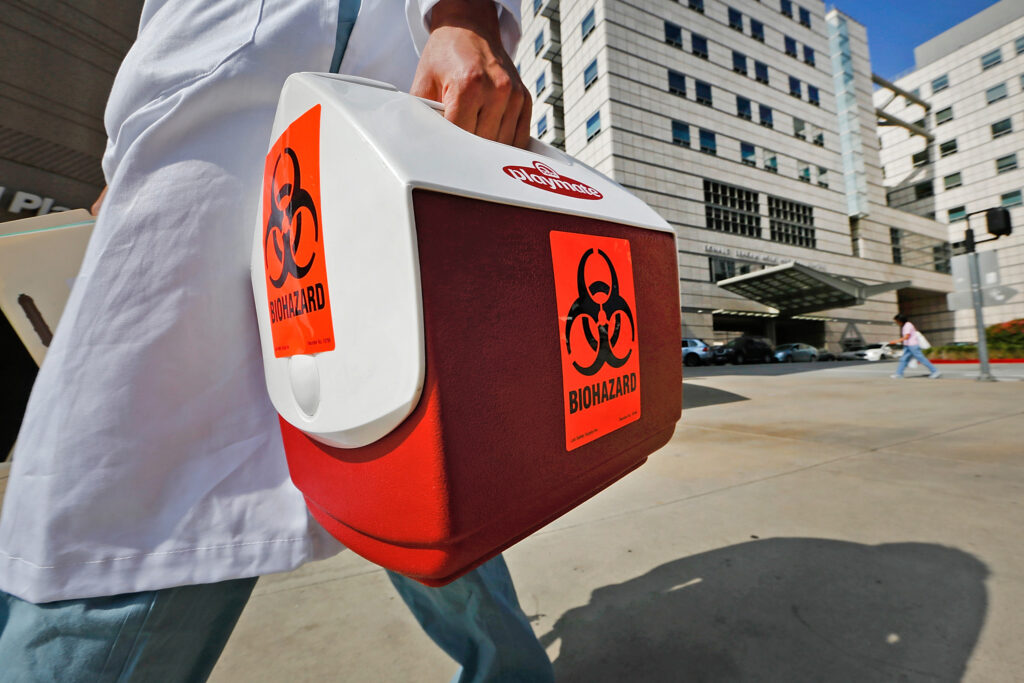 person carries box bearing 'biohazard' warning