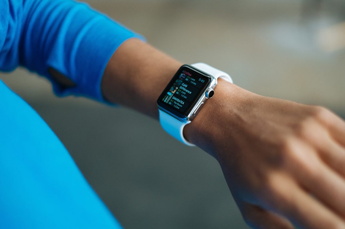 A smart watch on the wrist of a woman wearing a blue top