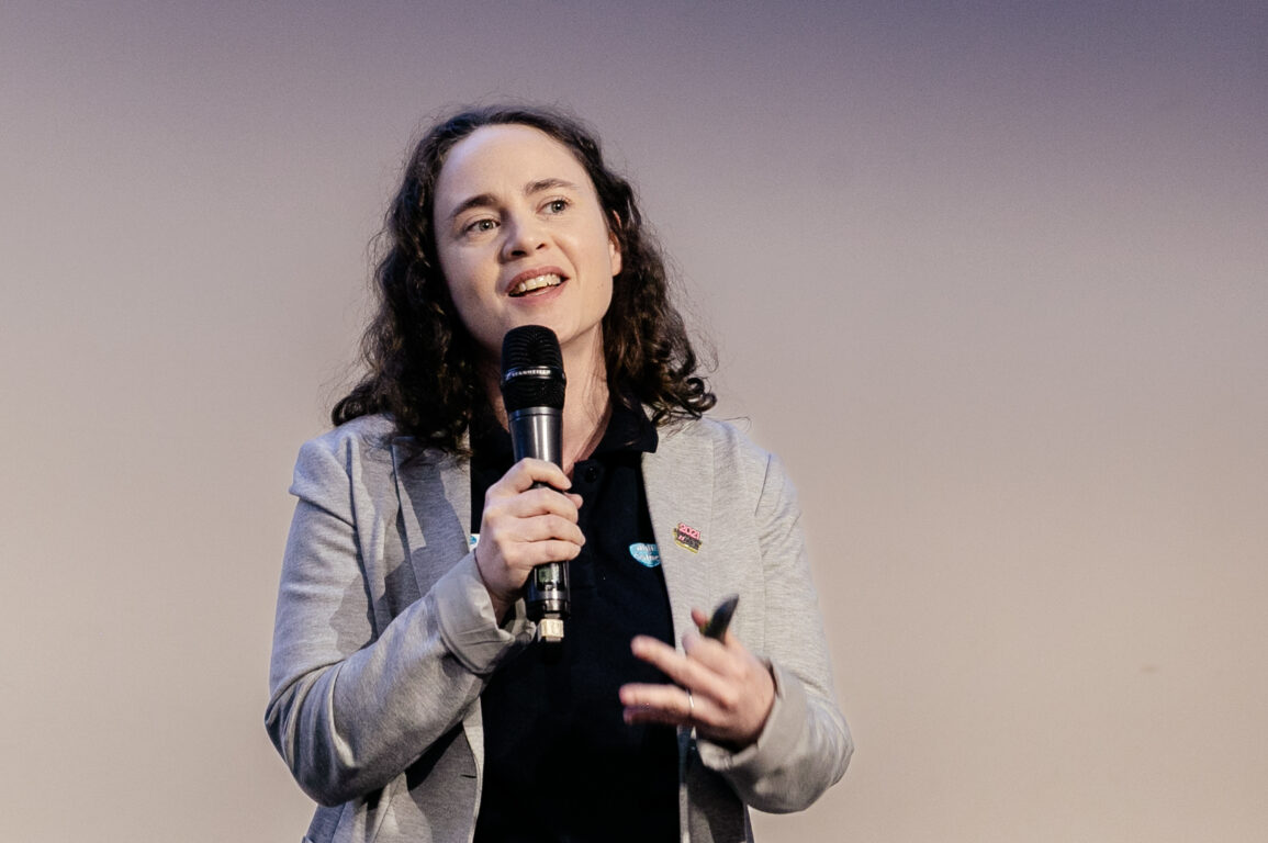 A woman holding a microphone presenting at a conference